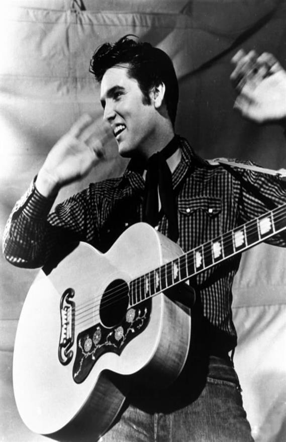 Elvis Presley is shown with his Gibson J-200 guitar in a 1957 MGM studio publicity photo.  Born in Tupelo, Miss., Elvis was an immediate sensation in the mid-1950s with his blend of blues rock and rockabilly.  Because of  his stage gyrations,  television producers initially refused to show him below the waist on screen.  Critics called him "Elvis the Pelvis," but his fans called him the "King of Rock 'n' Roll."  The Elvis empire grew with live performances, records, films and a grand estate in Memphis,Tenn.,  known worldwide as Graceland.  Elvis died at Graceland on Aug. 16, 1977.  He was 42.  (AP Photo)